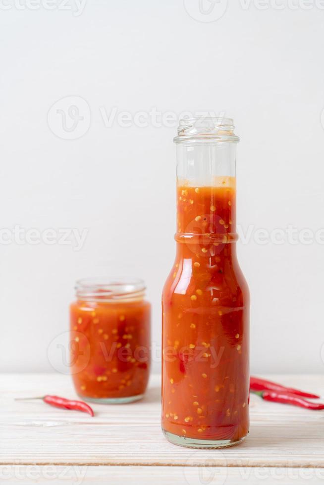 Chili or chili sauce in bottle and jar on wood background photo