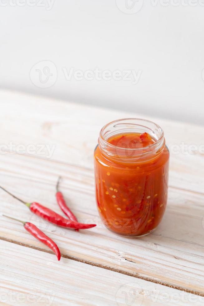 Chili or chili sauce in bottle and jar on wood background photo