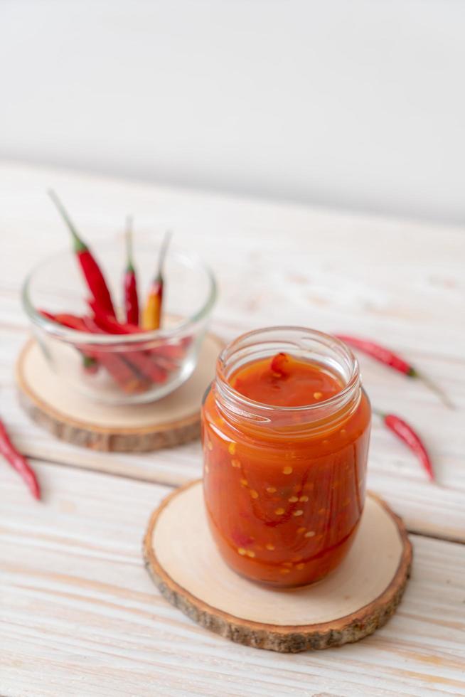 Chili or chili sauce in bottle and jar on wood background photo