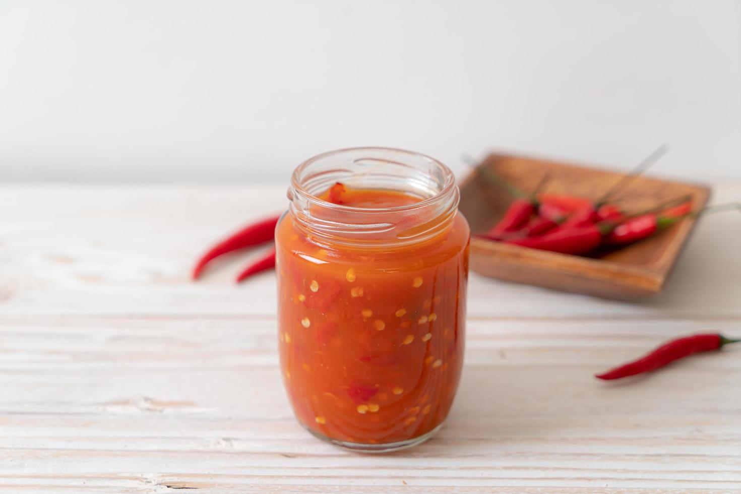 Chili or chili sauce in bottle and jar on wood background photo