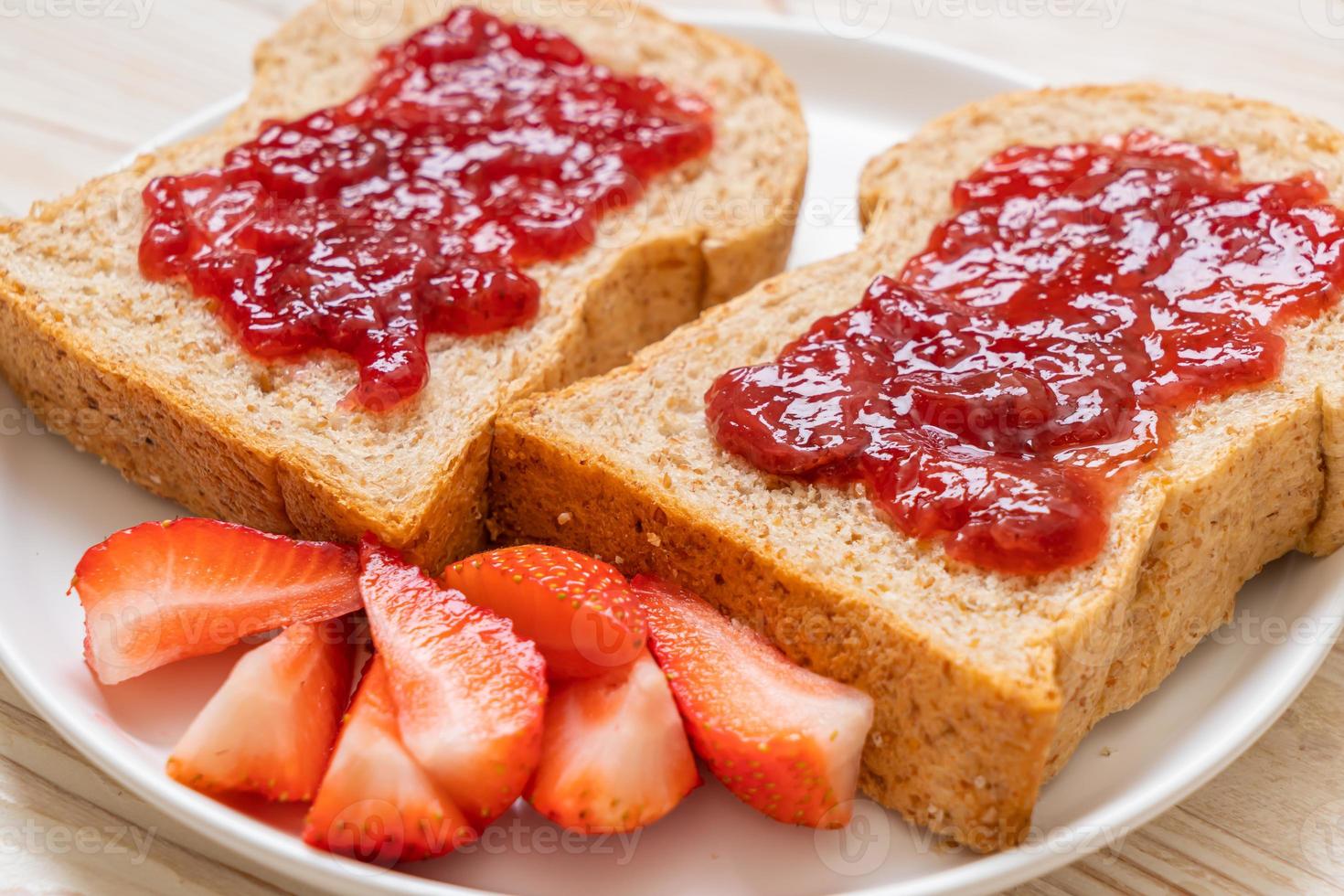 pan integral casero con mermelada de fresa y fresa fresca foto