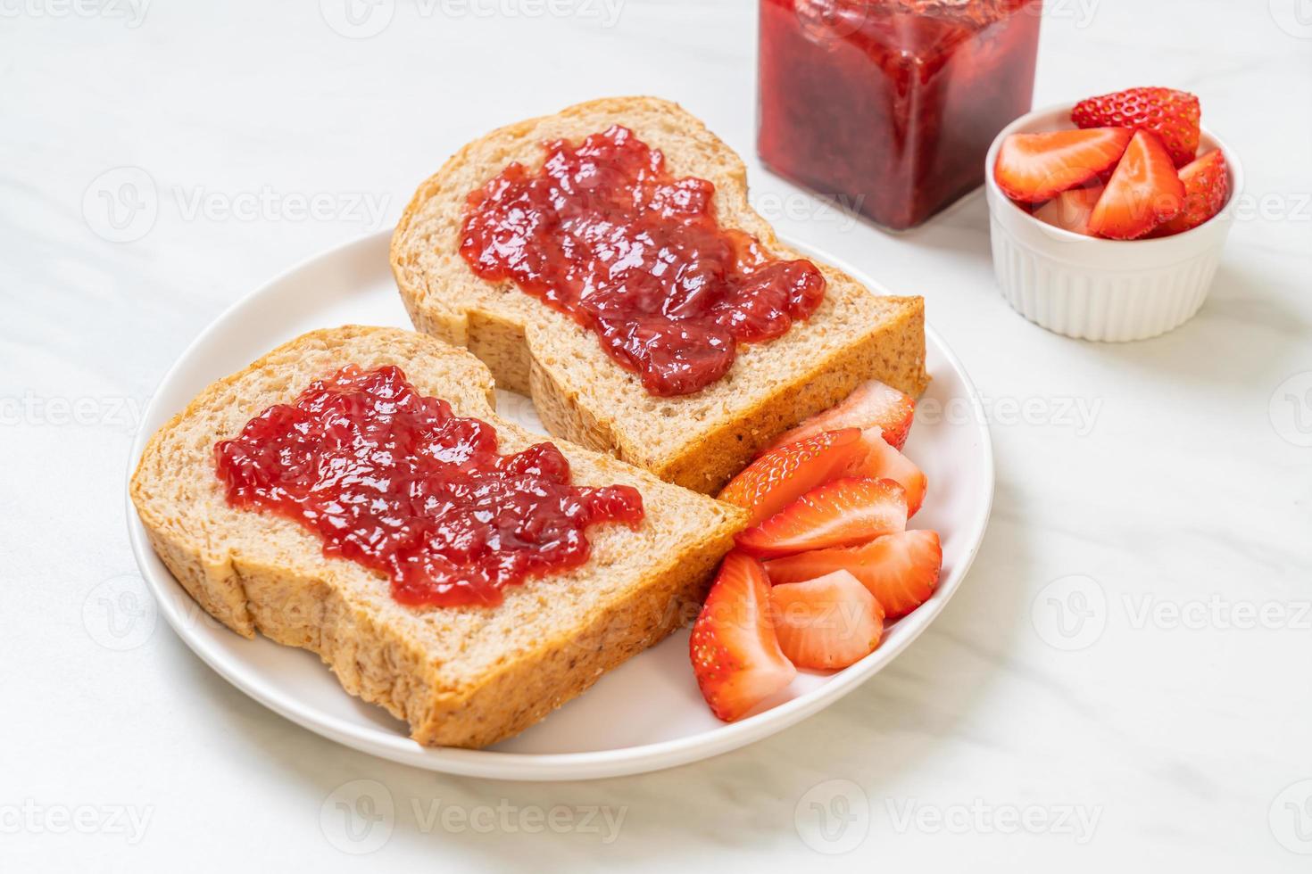 pan integral casero con mermelada de fresa y fresa fresca foto