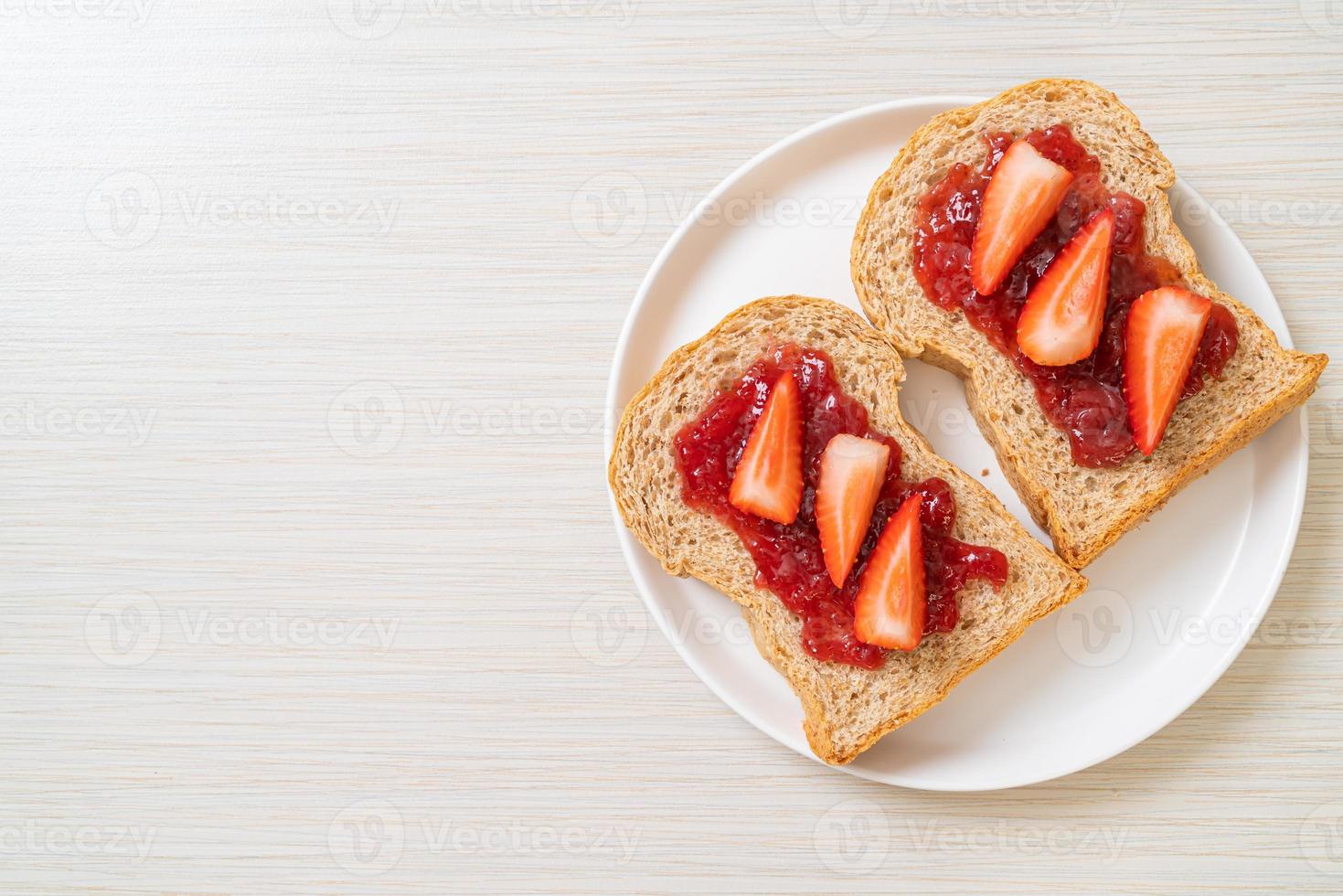 pan integral casero con mermelada de fresa y fresa fresca foto
