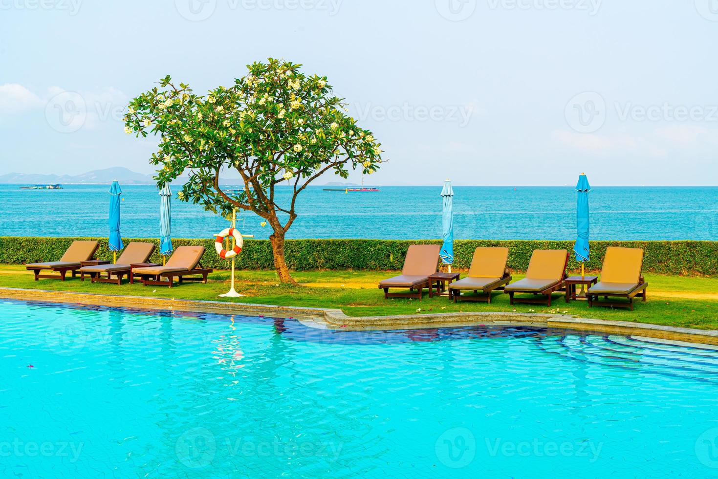 Piscina de sillas alrededor de la piscina con fondo de mar - vacaciones y concepto de vacaciones foto