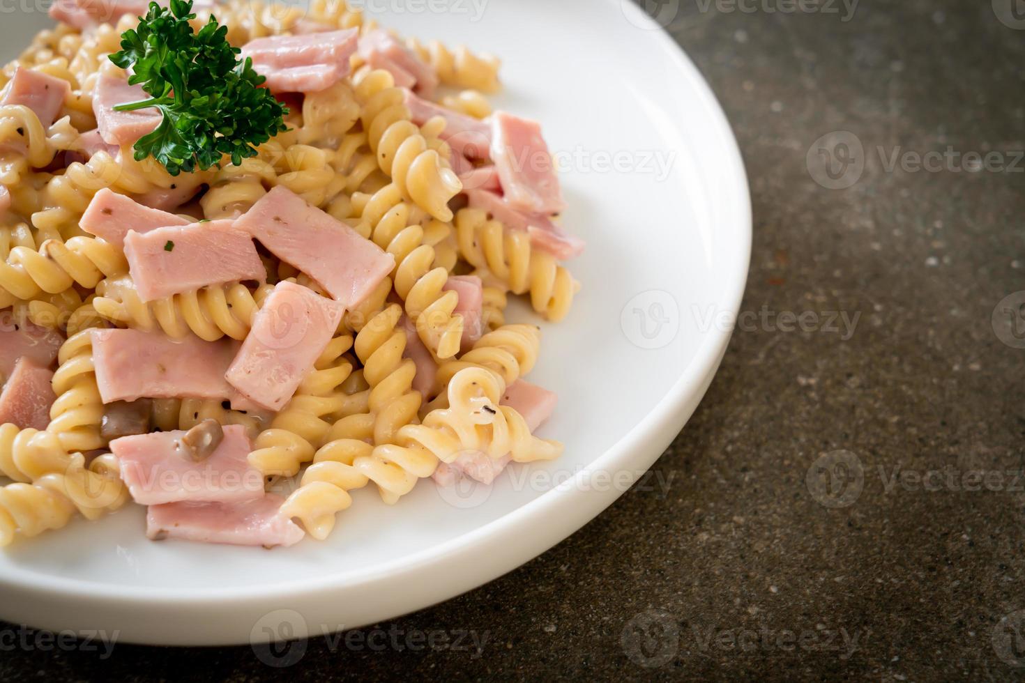 Spirali o salsa de crema de champiñones de pasta con jamón - estilo de comida italiana foto