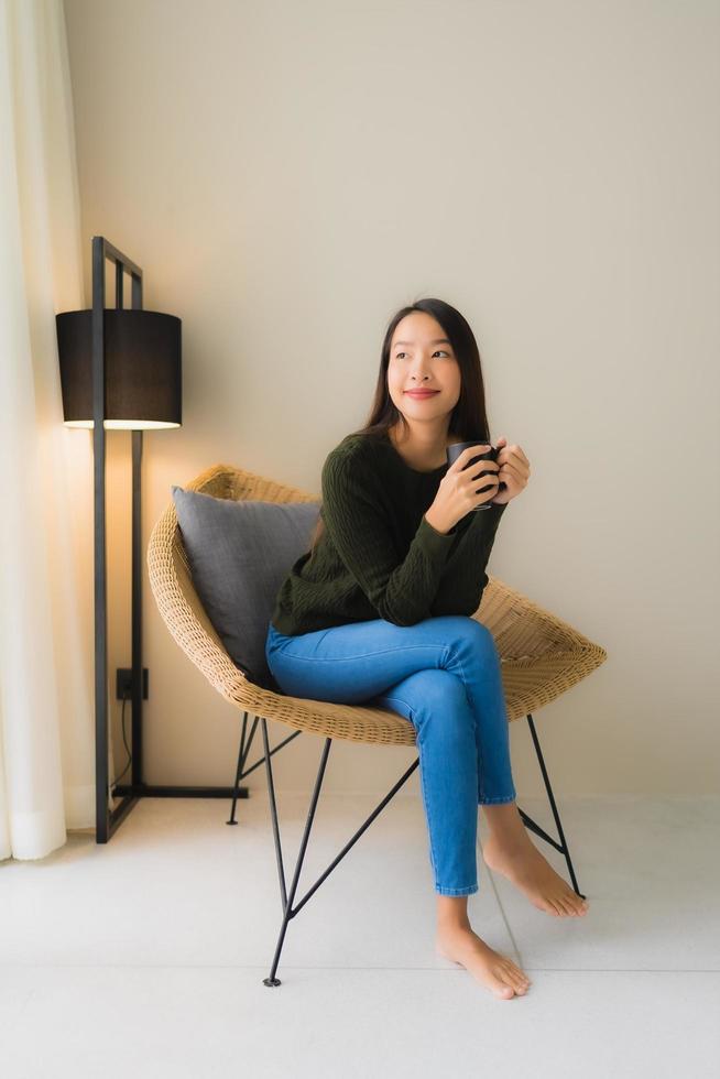 Portrait beautiful young asian woman hold coffee cup and sitting on sofa chair photo