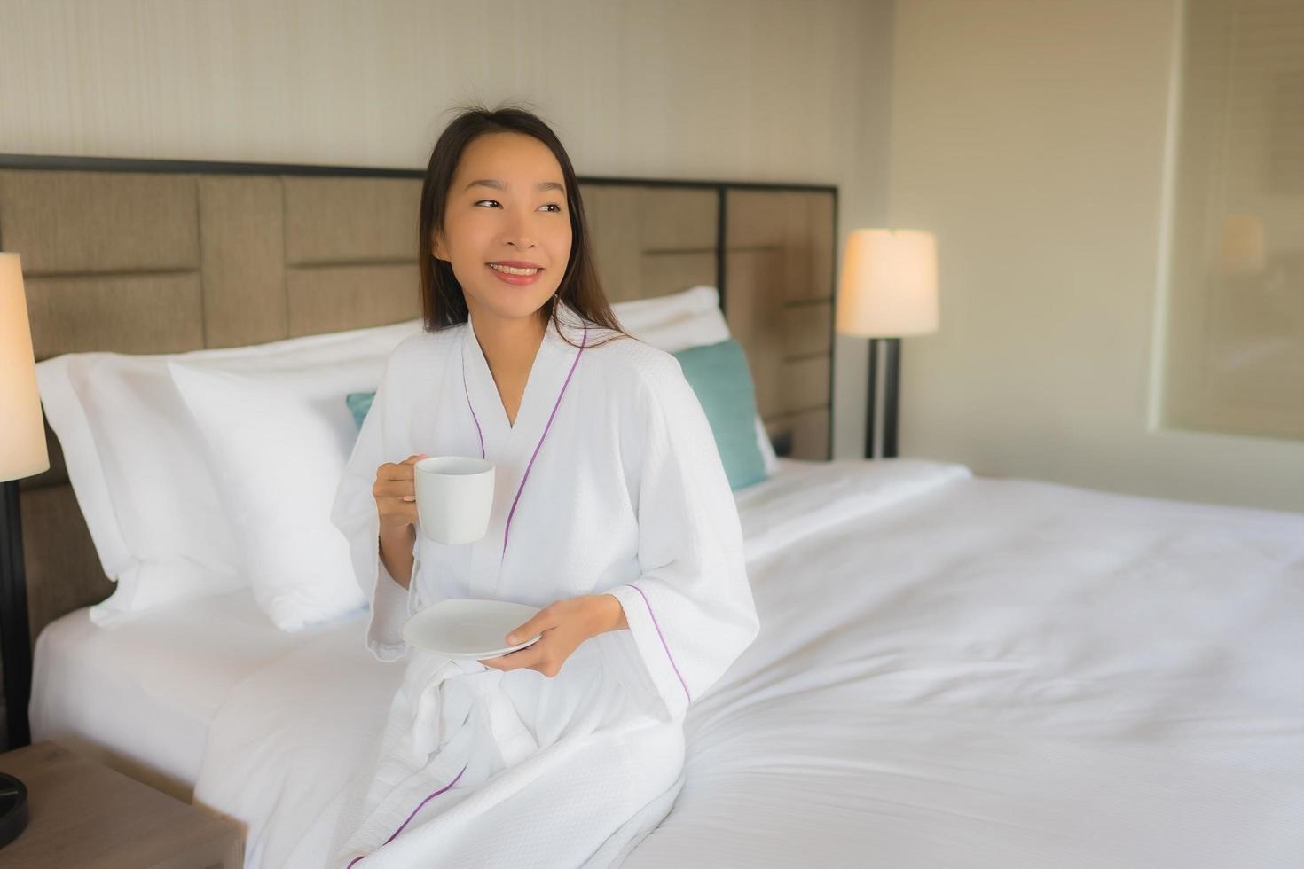 Portrait beautiful young asian women with coffee cup on bed photo