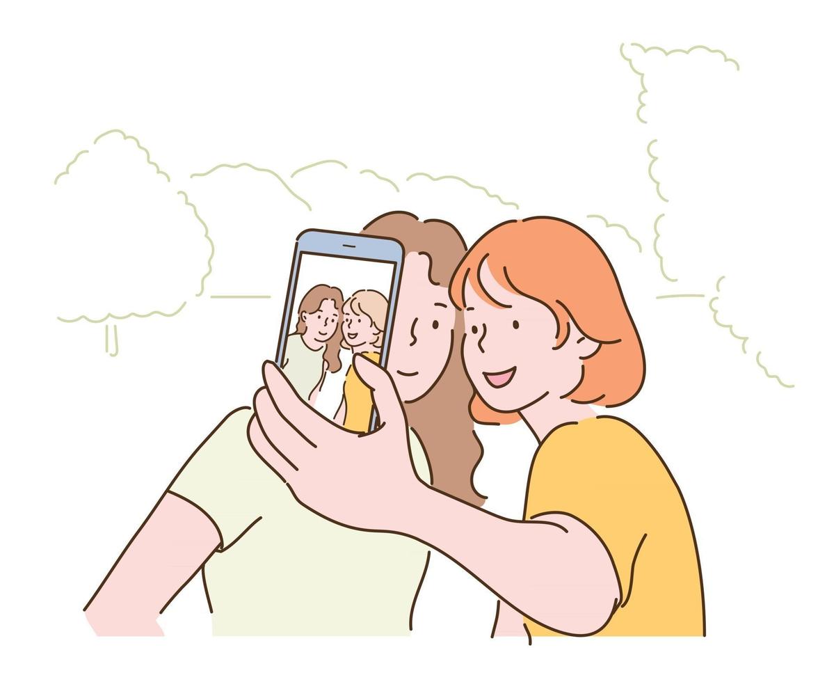 Two friends are taking a selfie with their mobile phones. hand drawn style vector design illustrations.