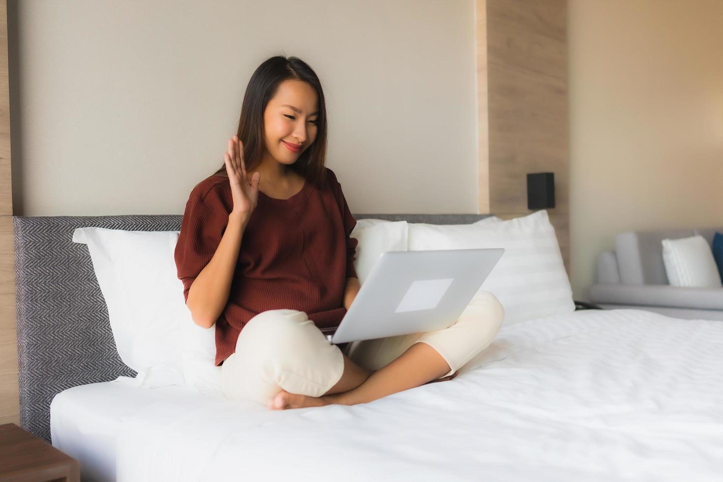 retrato, hermoso, joven, mujeres asiáticas, utilizar, computadora, y, teléfono móvil, en cama foto