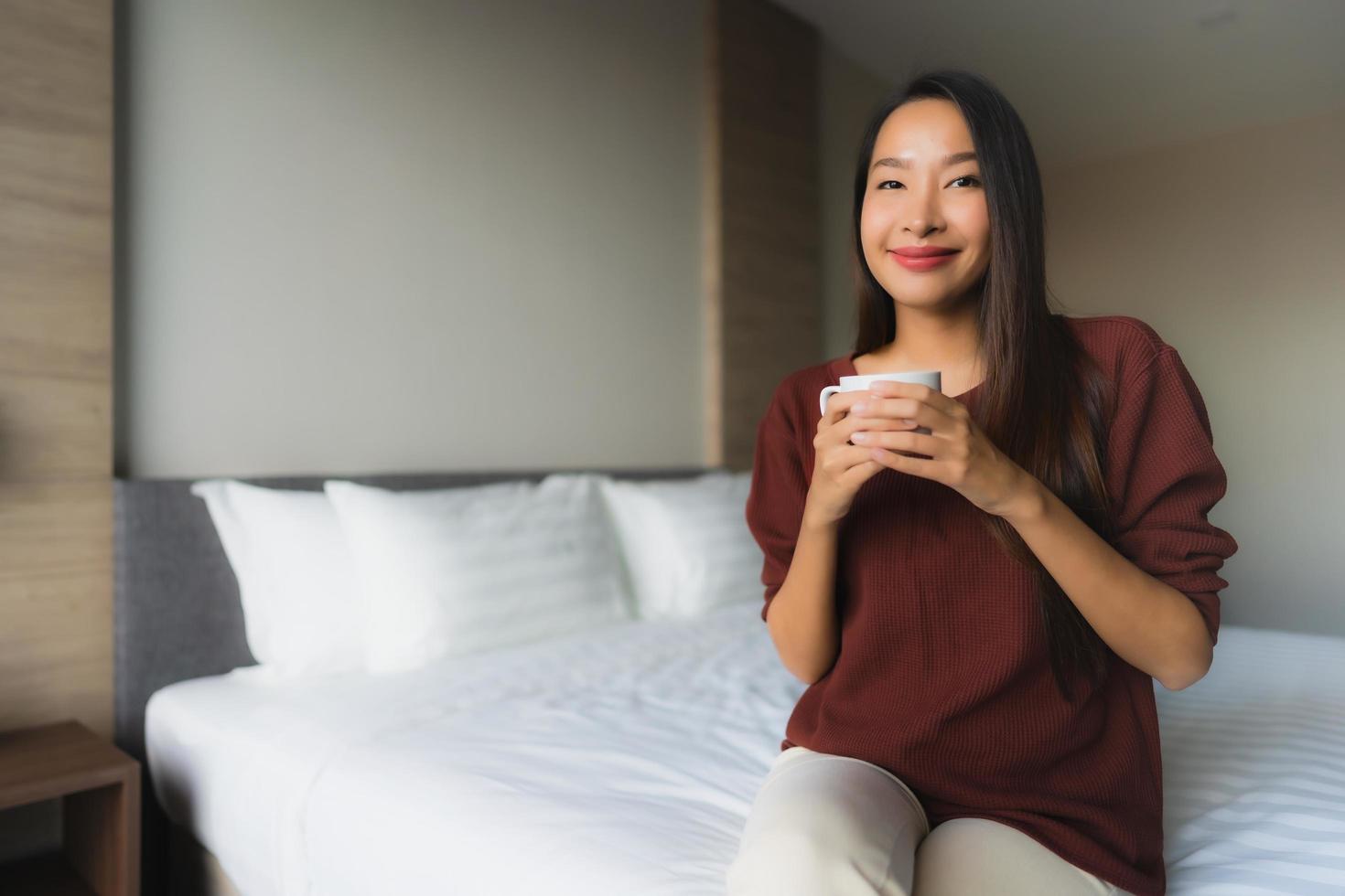 Portrait beautiful young asian women with coffee cup on bed photo