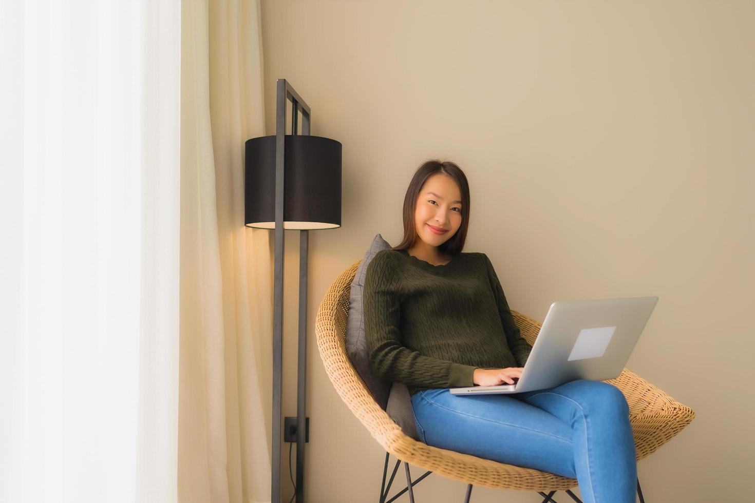 Portrait beautiful young asian women using computer or laptop for working and sitting on sofa chair photo