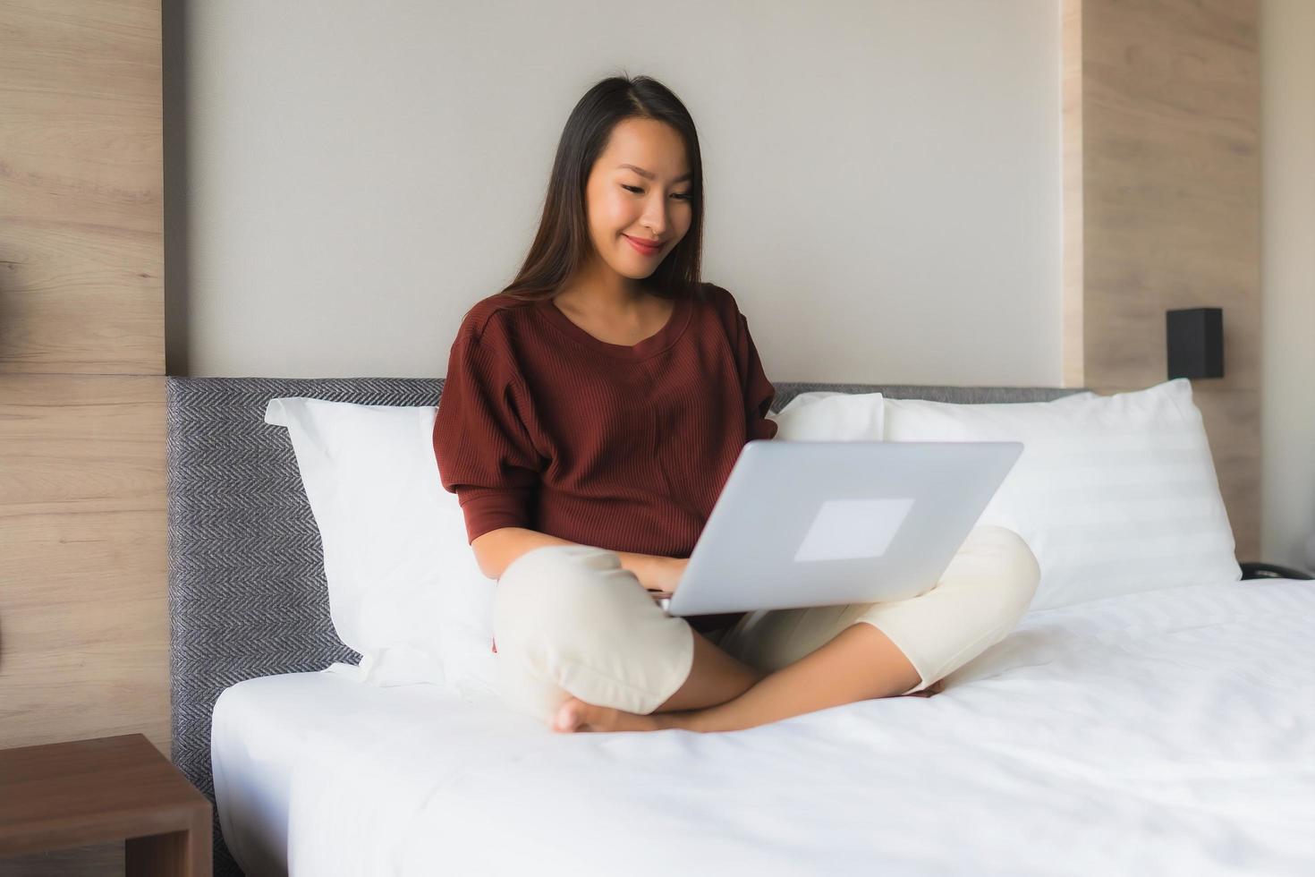 retrato, hermoso, joven, mujeres asiáticas, utilizar, computadora, y, teléfono móvil, en cama foto