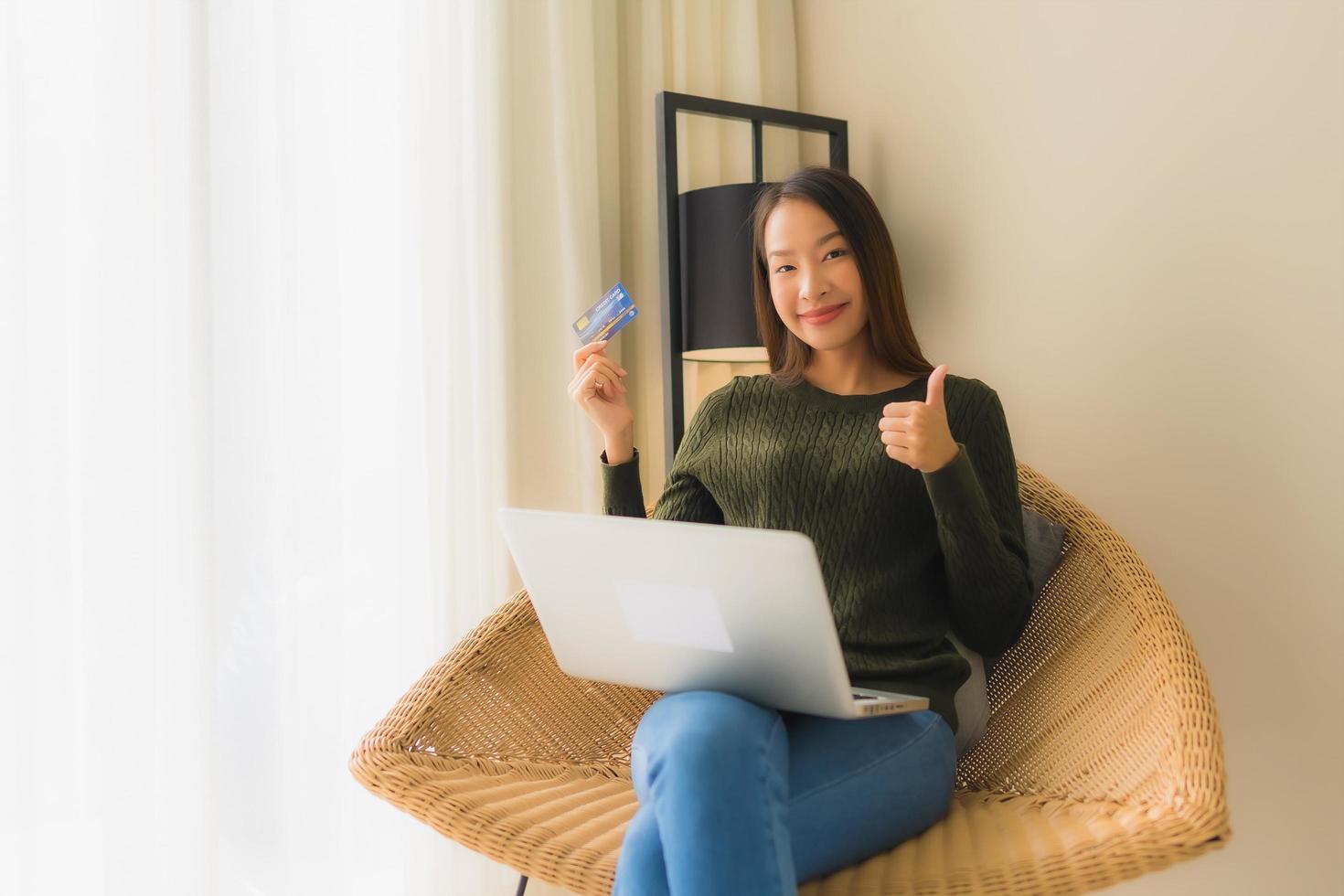 Retrato de hermosas mujeres asiáticas jóvenes usando computadora portátil o teléfono inteligente y móvil con tarjeta de crédito para compras en línea foto