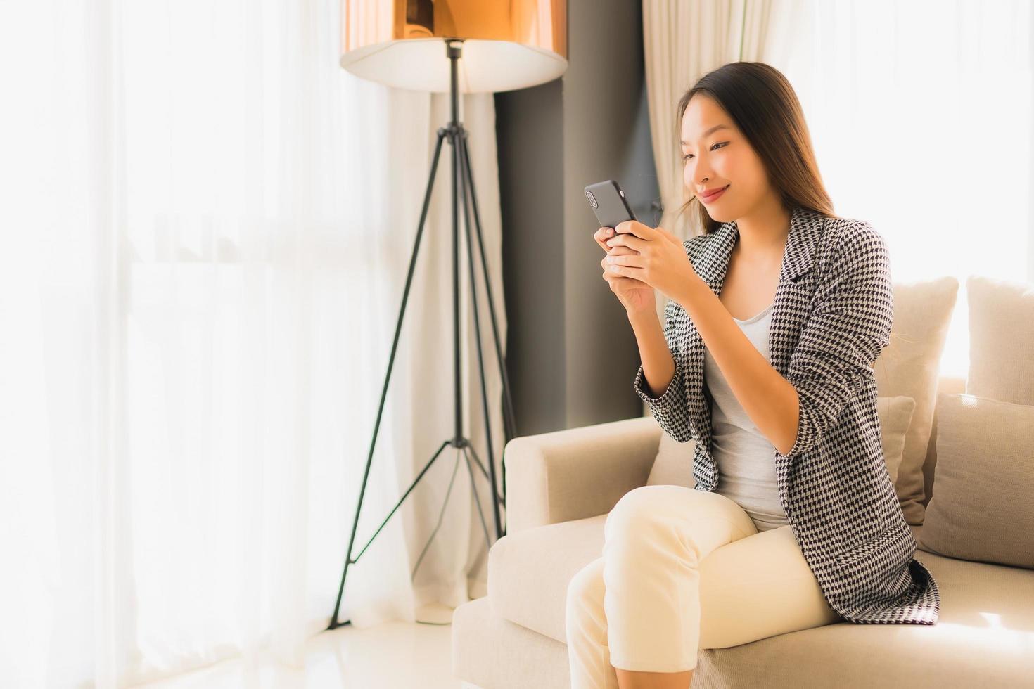 retrato, hermoso, joven, mujeres asiáticas, utilizar, hablar, teléfono móvil, y, sentar sofá foto