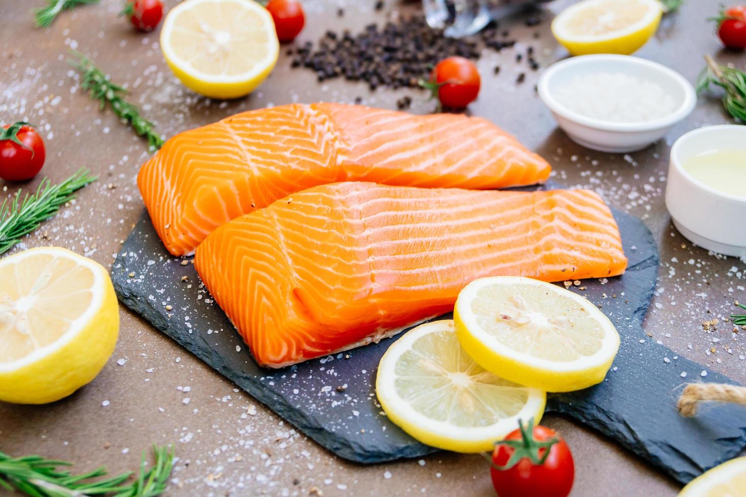 Filete de carne de salmón crudo y fresco sobre pizarra de piedra negra foto