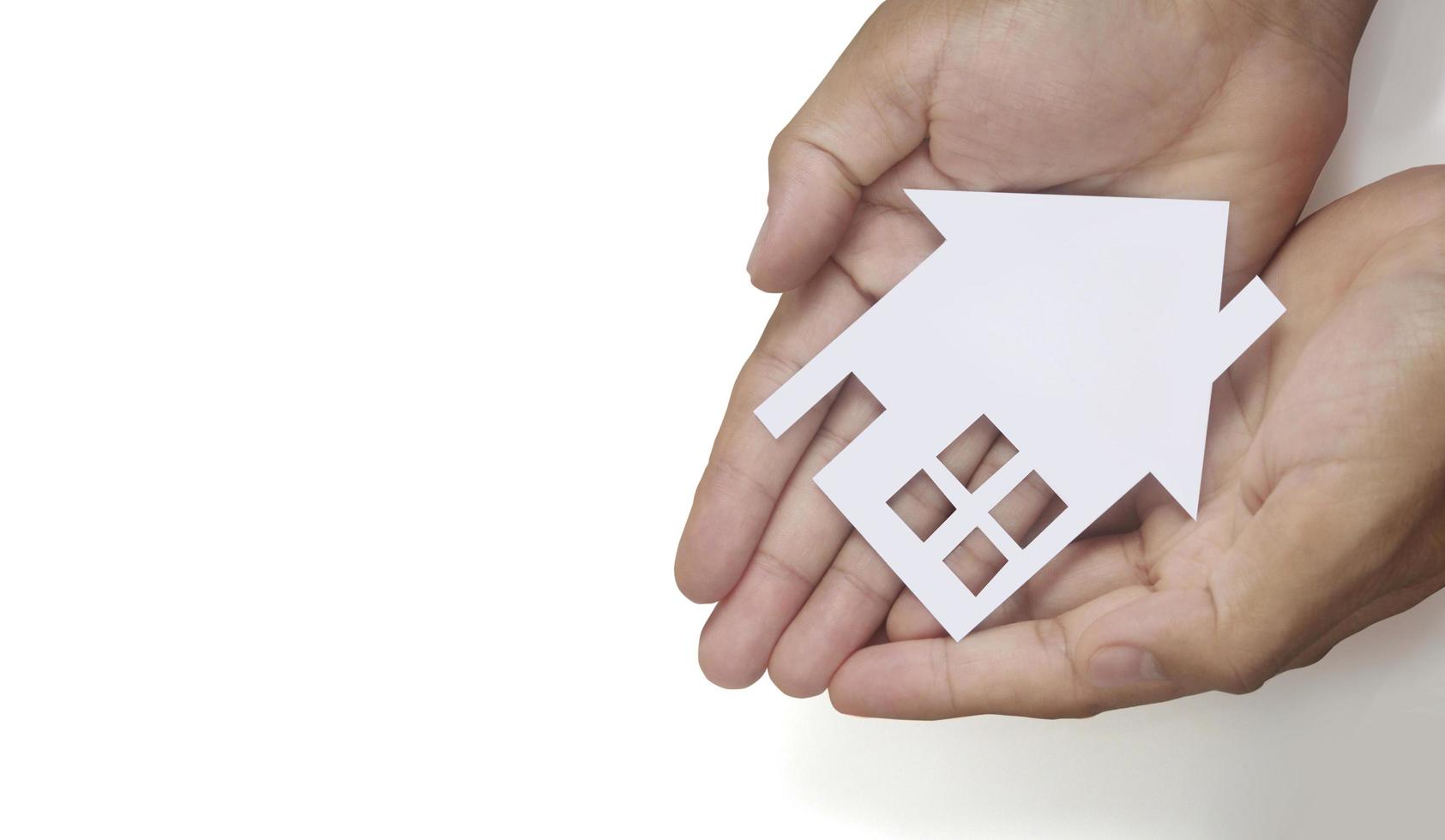 Hands holding paper house, family home protecting insurance concept photo