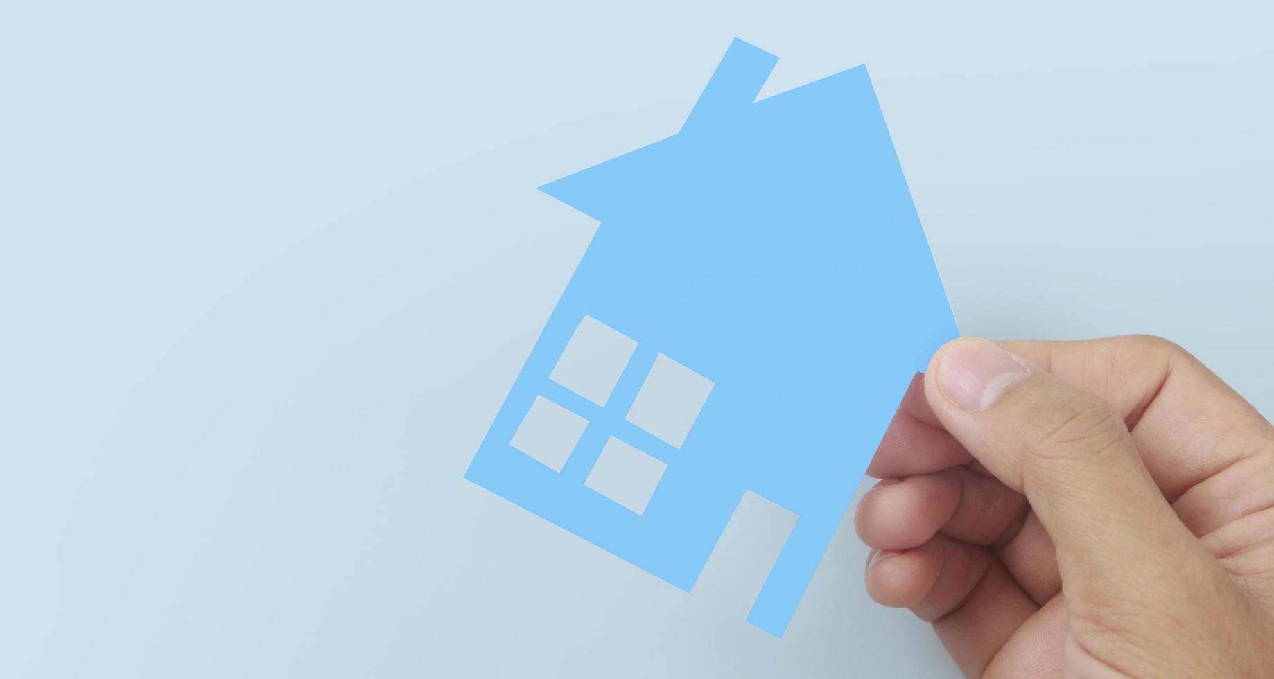 Hands holding paper house, family home protecting insurance concept photo