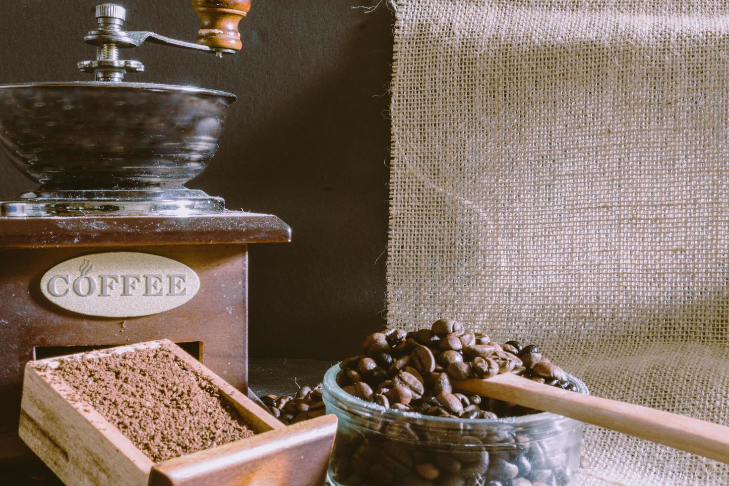 Still life with coffee beans and old coffee mill on the rustic background photo