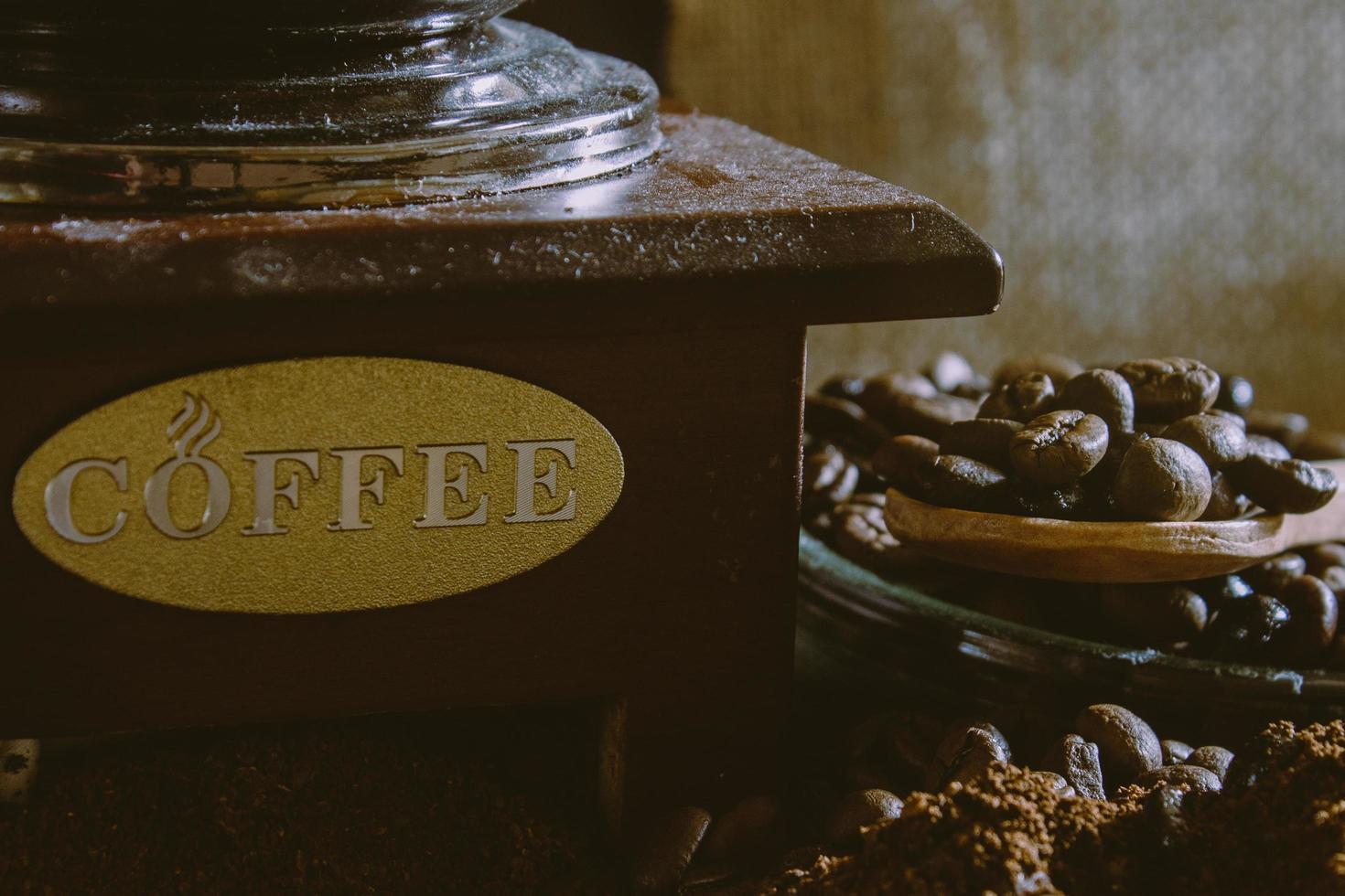 Bodegón con granos de café y antiguo molino de café en el fondo rústico foto