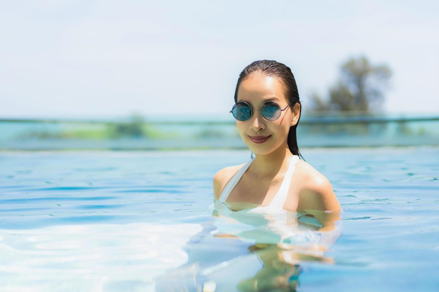 Beautiful young asian woman happy and smile in swimming pool for relax travel and vacation photo