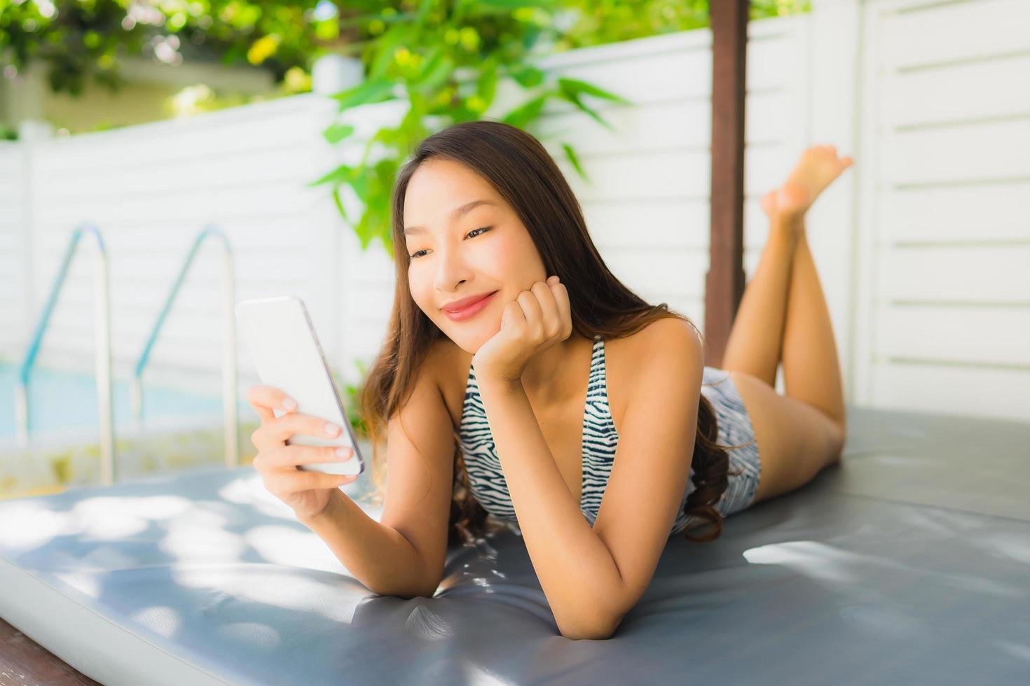 Portrait beautiful young asian woman happy smile talk mobile phone around swimming pool photo