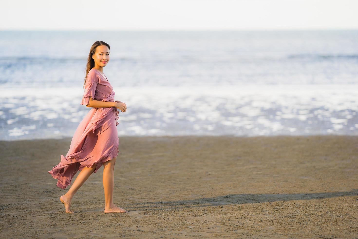 Portrait young beautiful asian woman walk smile and happy on the beach sea and ocean photo