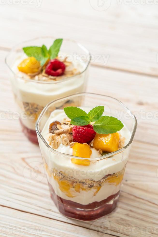 mango fresco casero y frambuesa fresca con yogur y granola - estilo de comida saludable foto