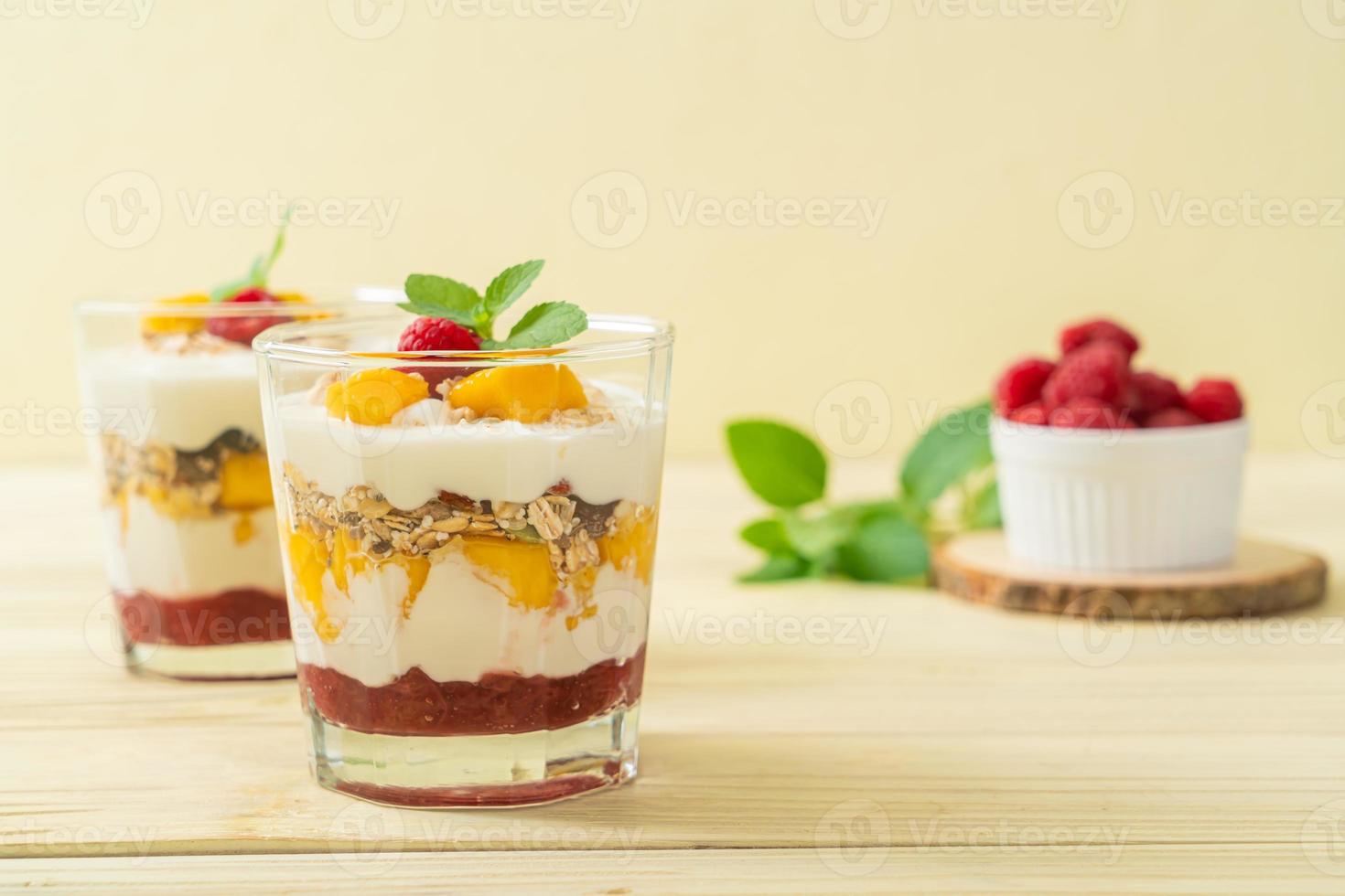 mango fresco casero y frambuesa fresca con yogur y granola - estilo de comida saludable foto