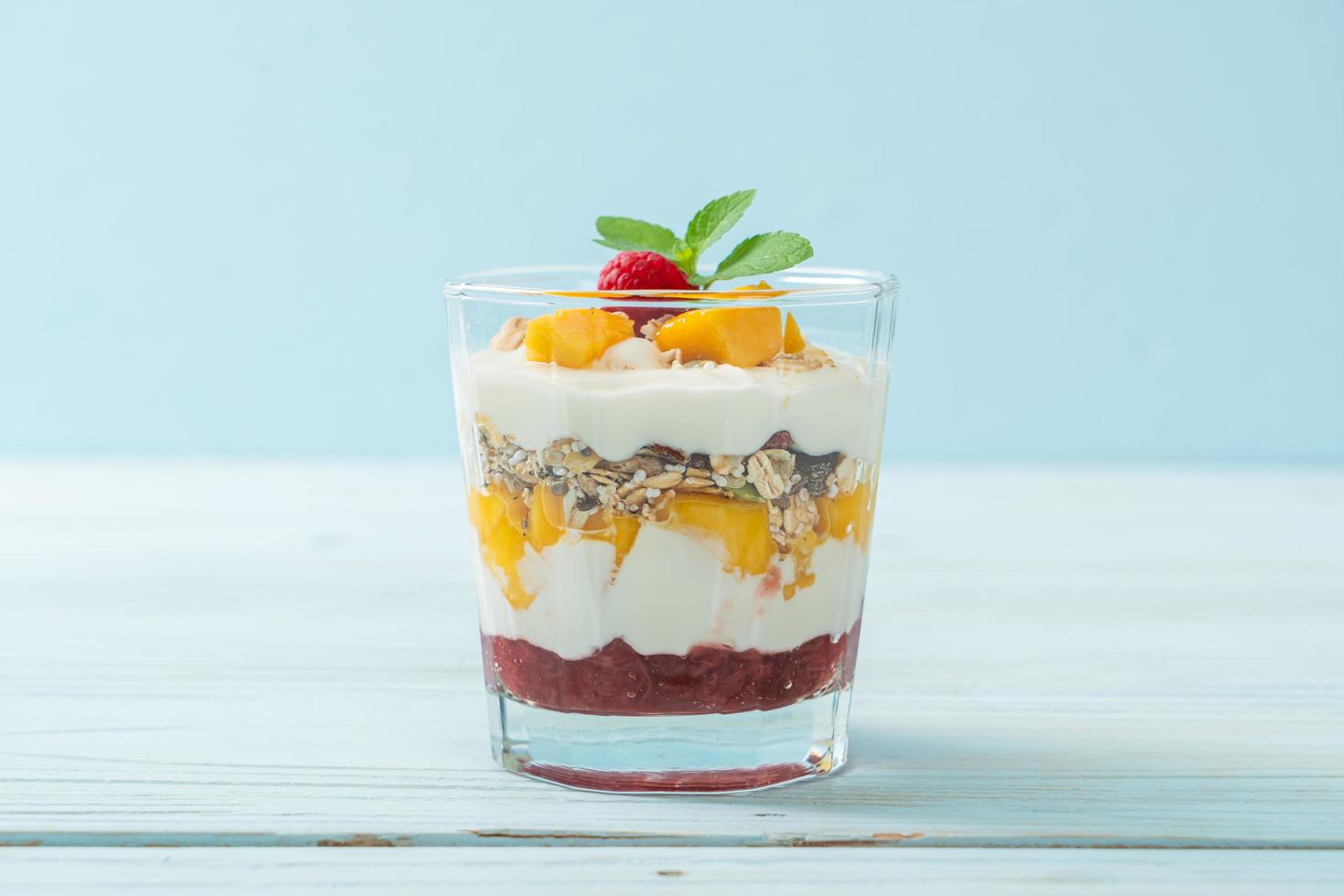 mango fresco casero y frambuesa fresca con yogur y granola - estilo de comida saludable foto