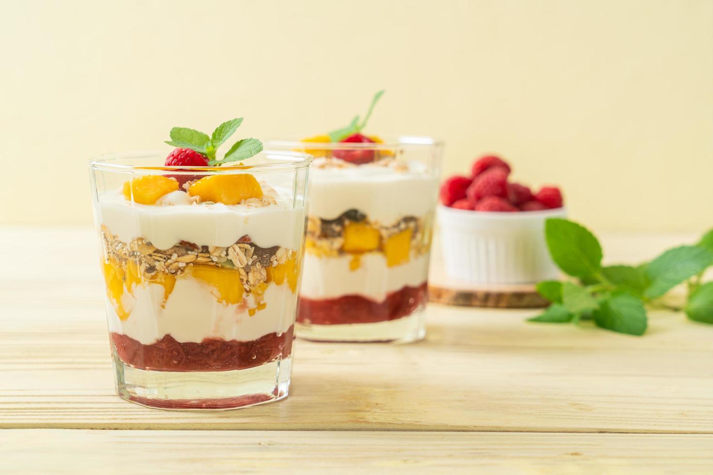 mango fresco casero y frambuesa fresca con yogur y granola - estilo de comida saludable foto