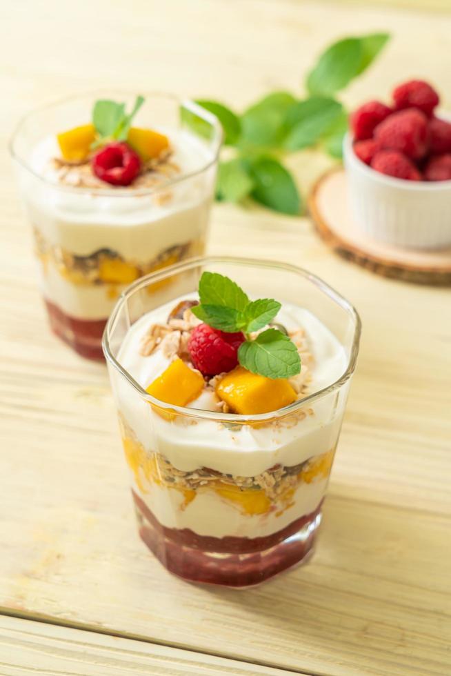 mango fresco casero y frambuesa fresca con yogur y granola - estilo de comida saludable foto