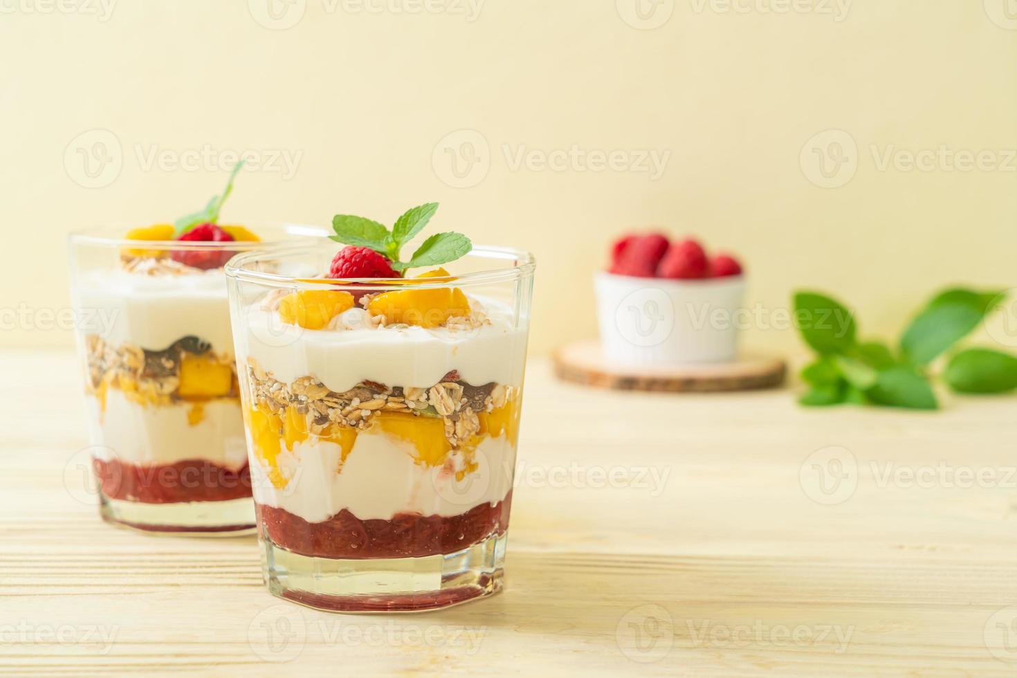 mango fresco casero y frambuesa fresca con yogur y granola - estilo de comida saludable foto