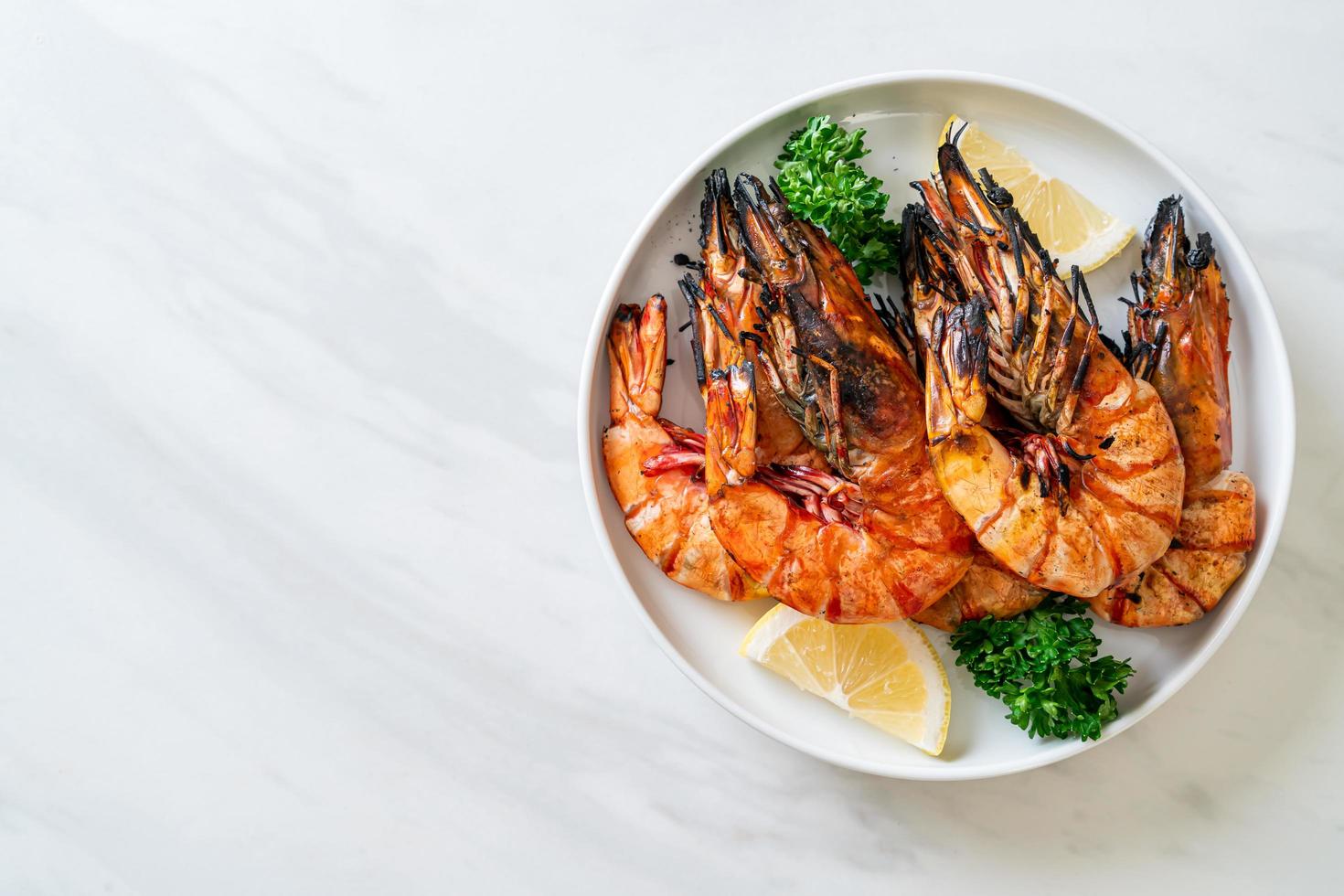 Grilled tiger prawns or shrimps with lemon on a plate photo