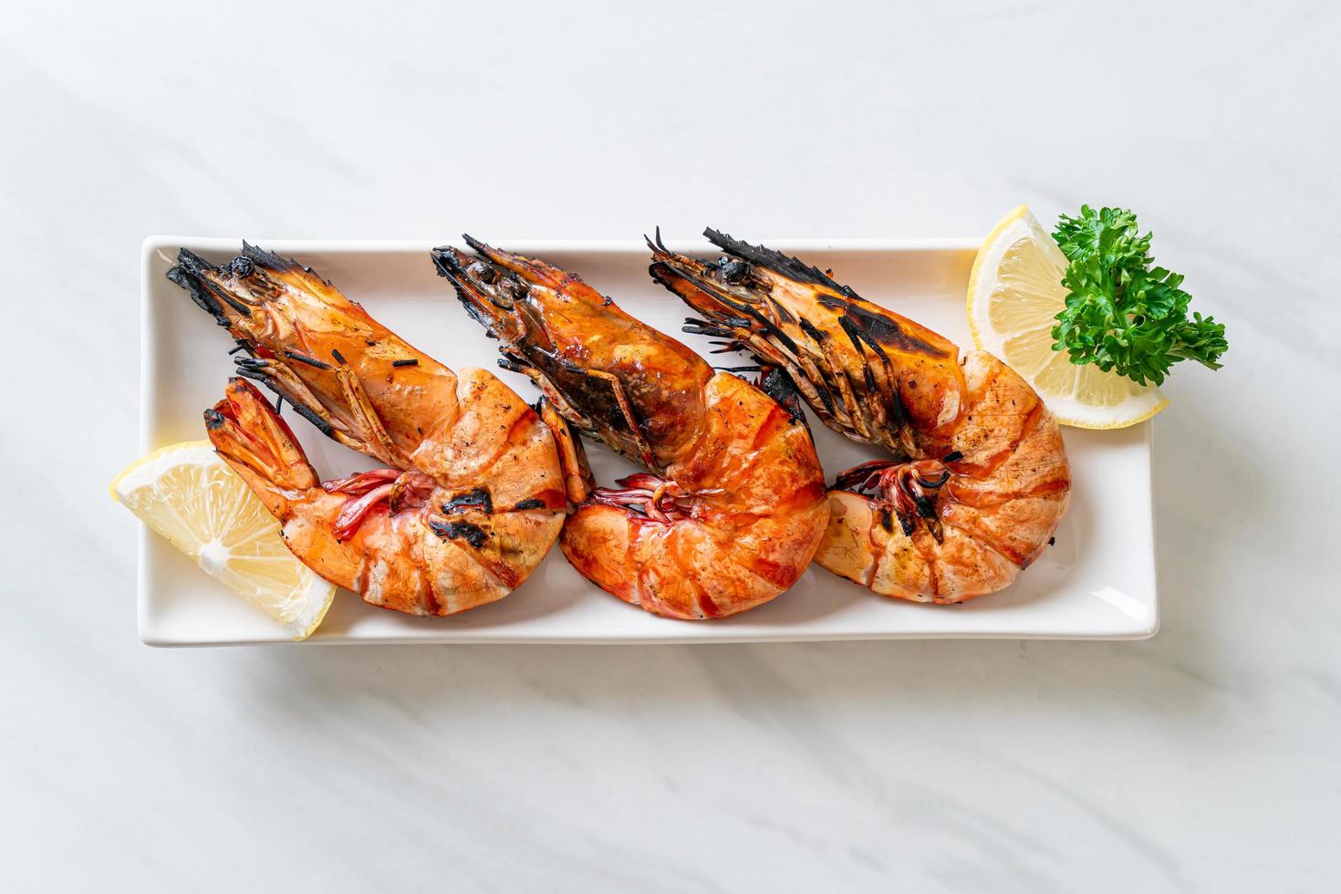 Grilled tiger prawns or shrimps with lemon on a plate photo