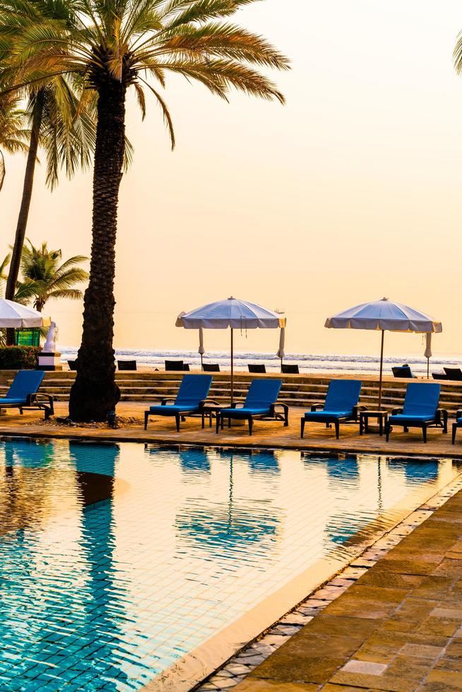 Hermosa palmera con sombrilla piscina en hotel resort de lujo al amanecer - concepto de vacaciones y vacaciones foto