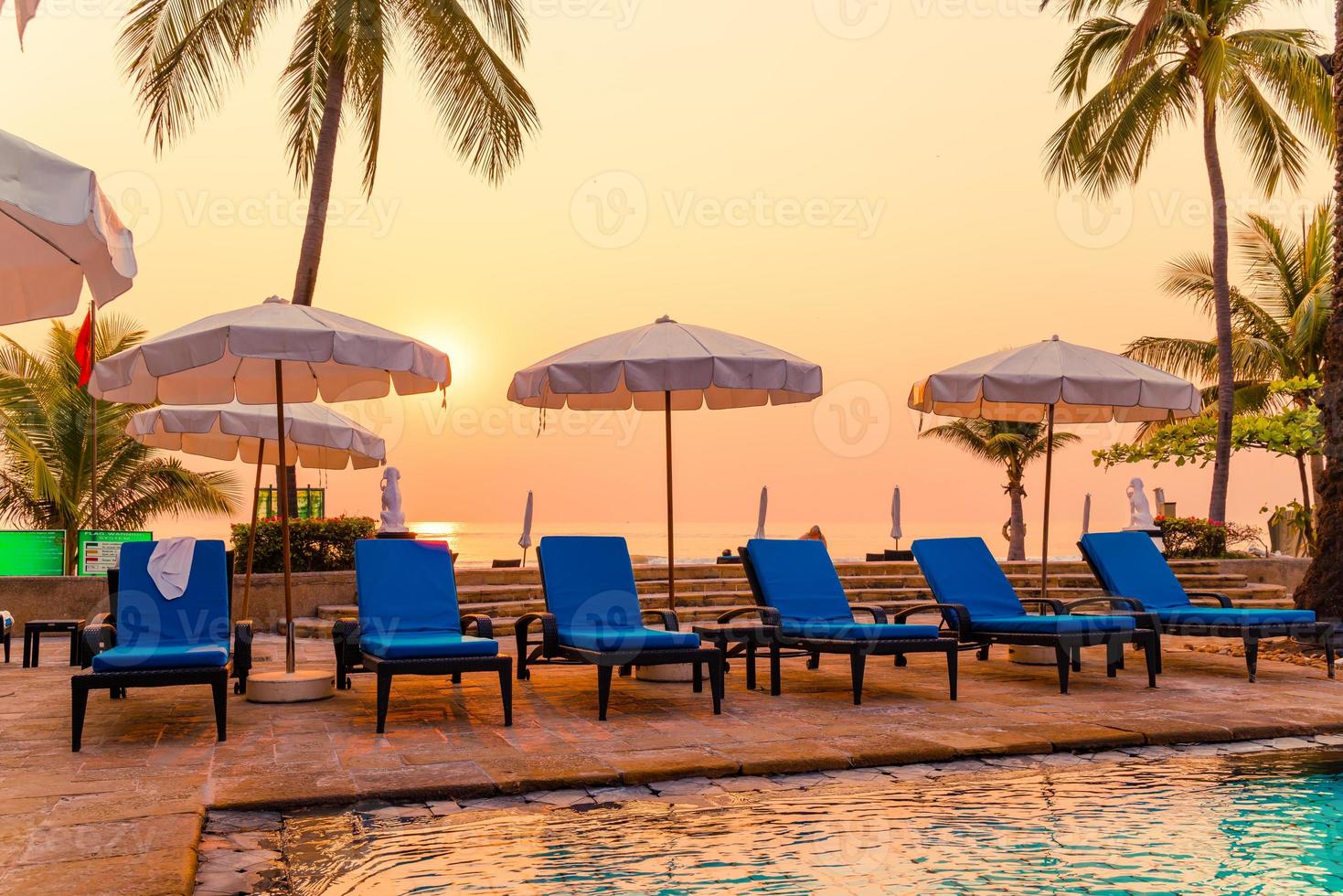 Hermosa palmera con sombrilla piscina en hotel resort de lujo al amanecer - concepto de vacaciones y vacaciones foto