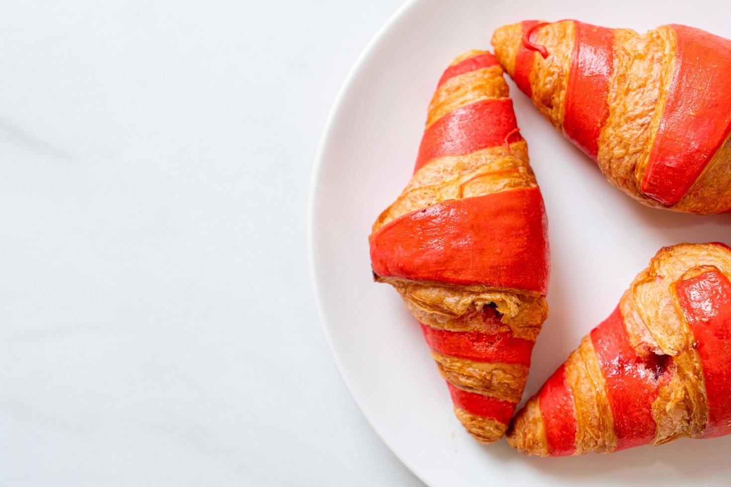 Croissant fresco con salsa de mermelada de fresa en la placa foto