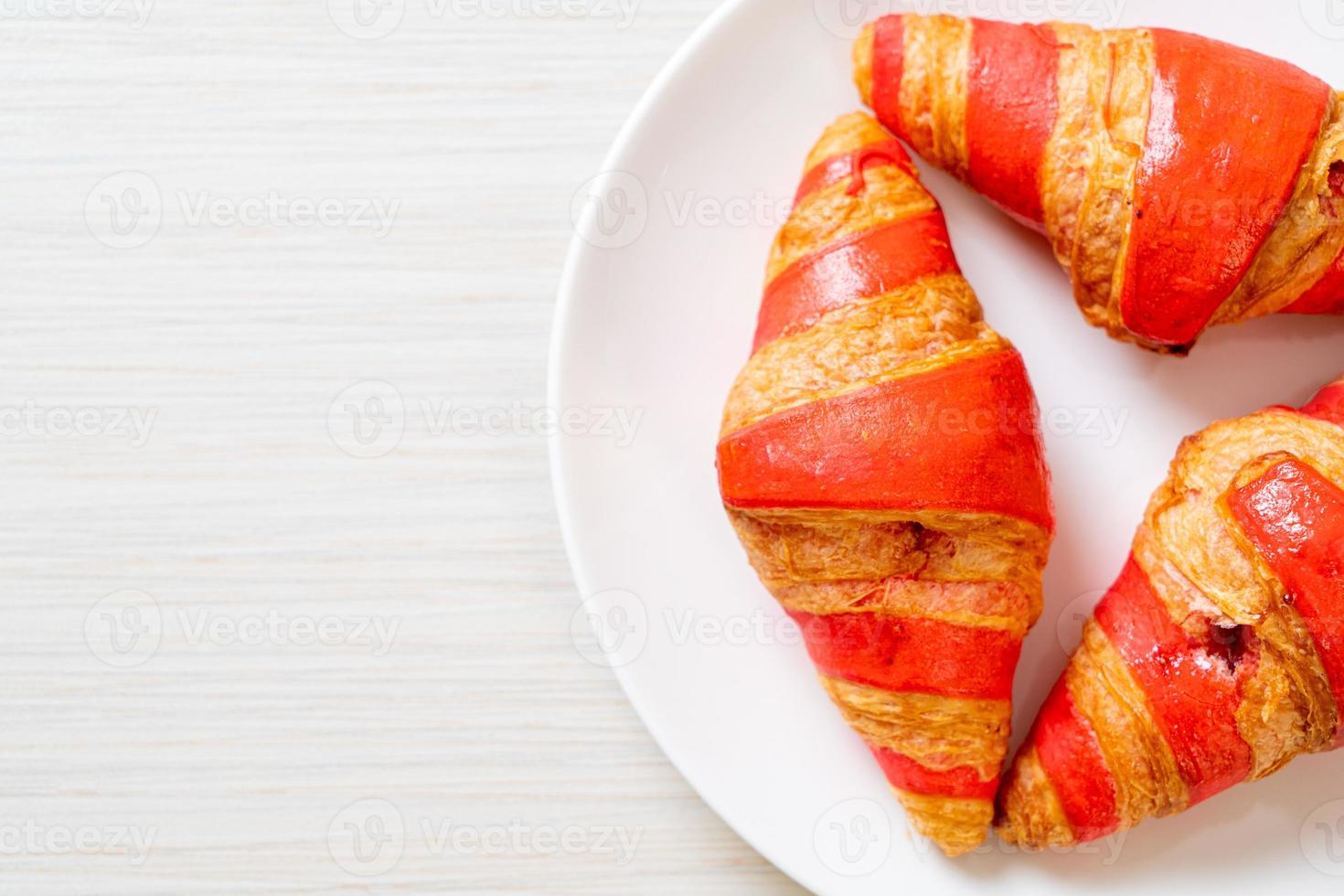 Croissant fresco con salsa de mermelada de fresa en la placa foto