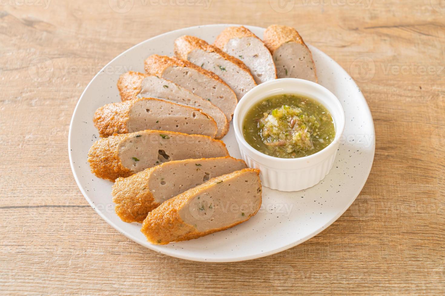 Fried Chinese fish cake or fish ball line sliced with spicy seafood dipping sauce photo