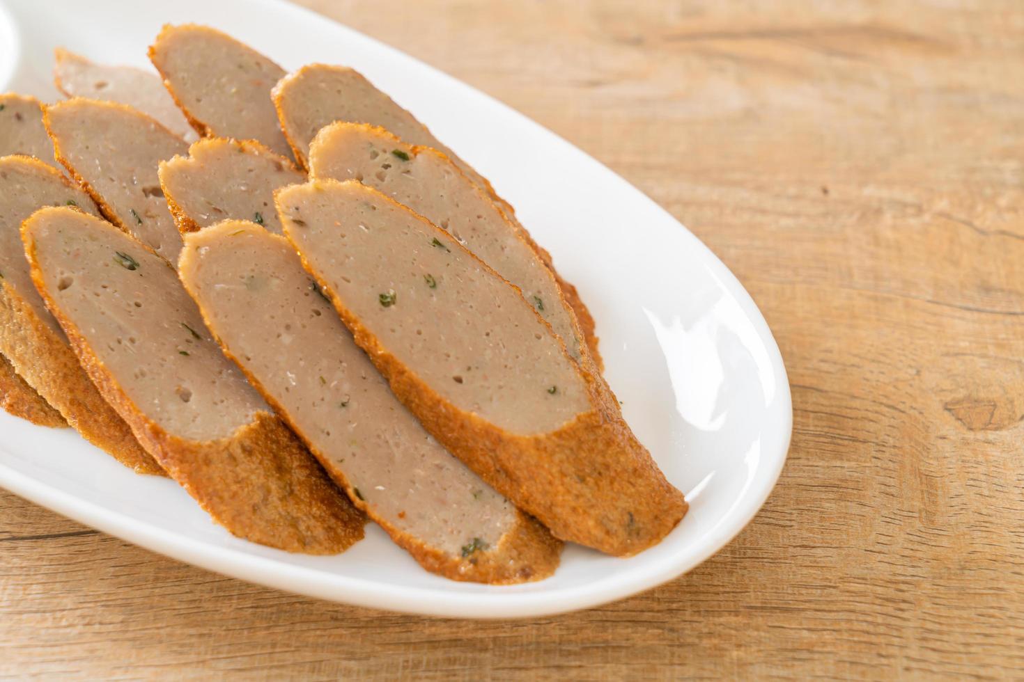 Fried Chinese fish cake or fish ball line sliced with spicy seafood dipping sauce photo