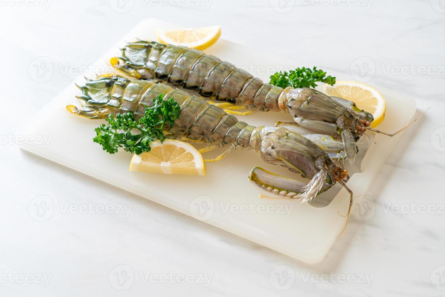 Fresh mantis shrimp with lemon on a board photo