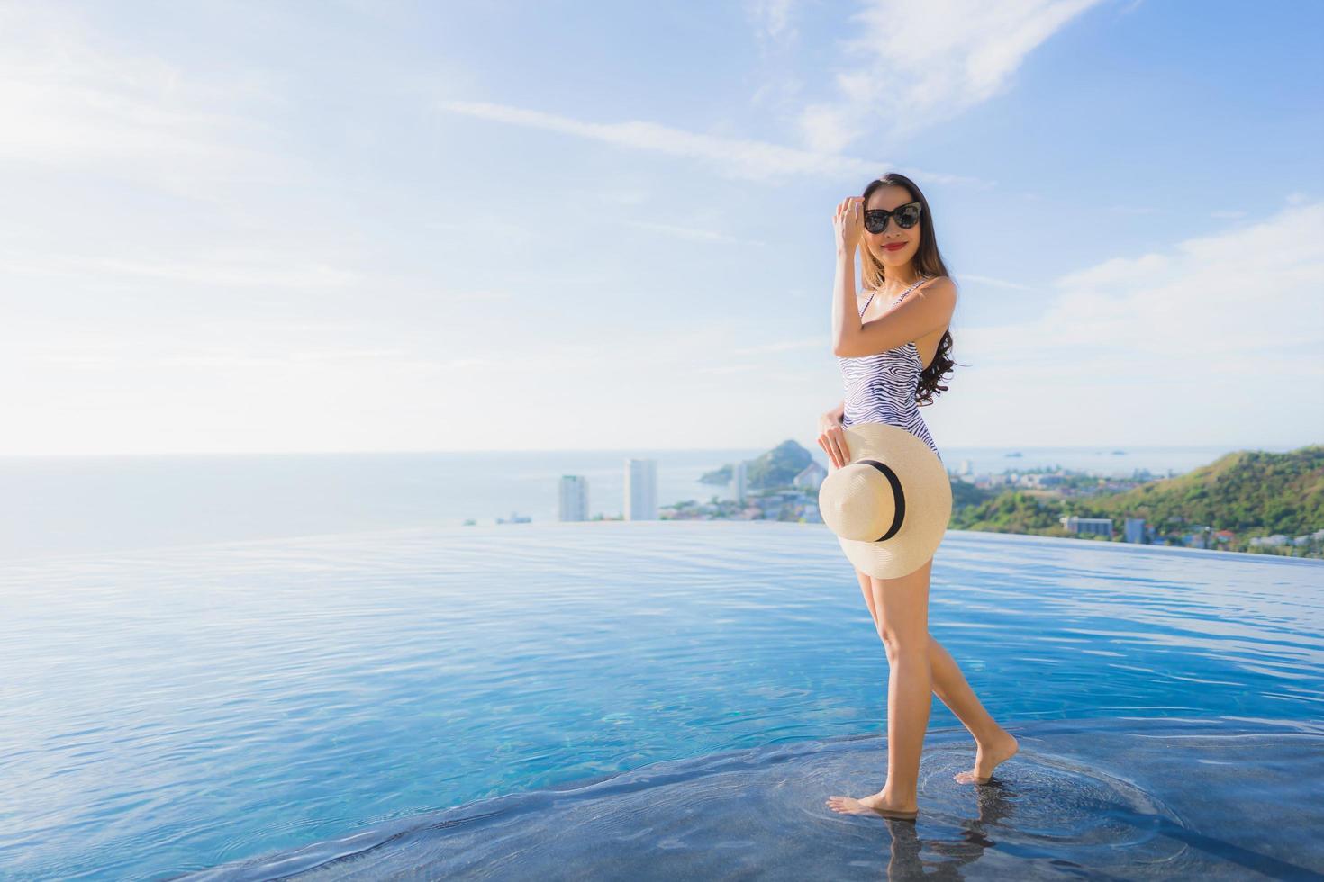 Portrait beautiful young asian woman smile happy relax around swimming pool in hotel resort with sea and ocean view photo