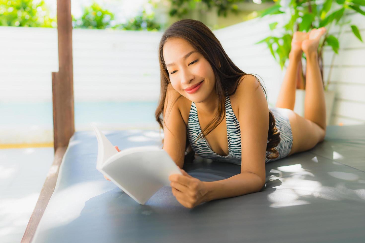 Portrait beautiful young asian woman happy smile with reading book around swimming pool photo