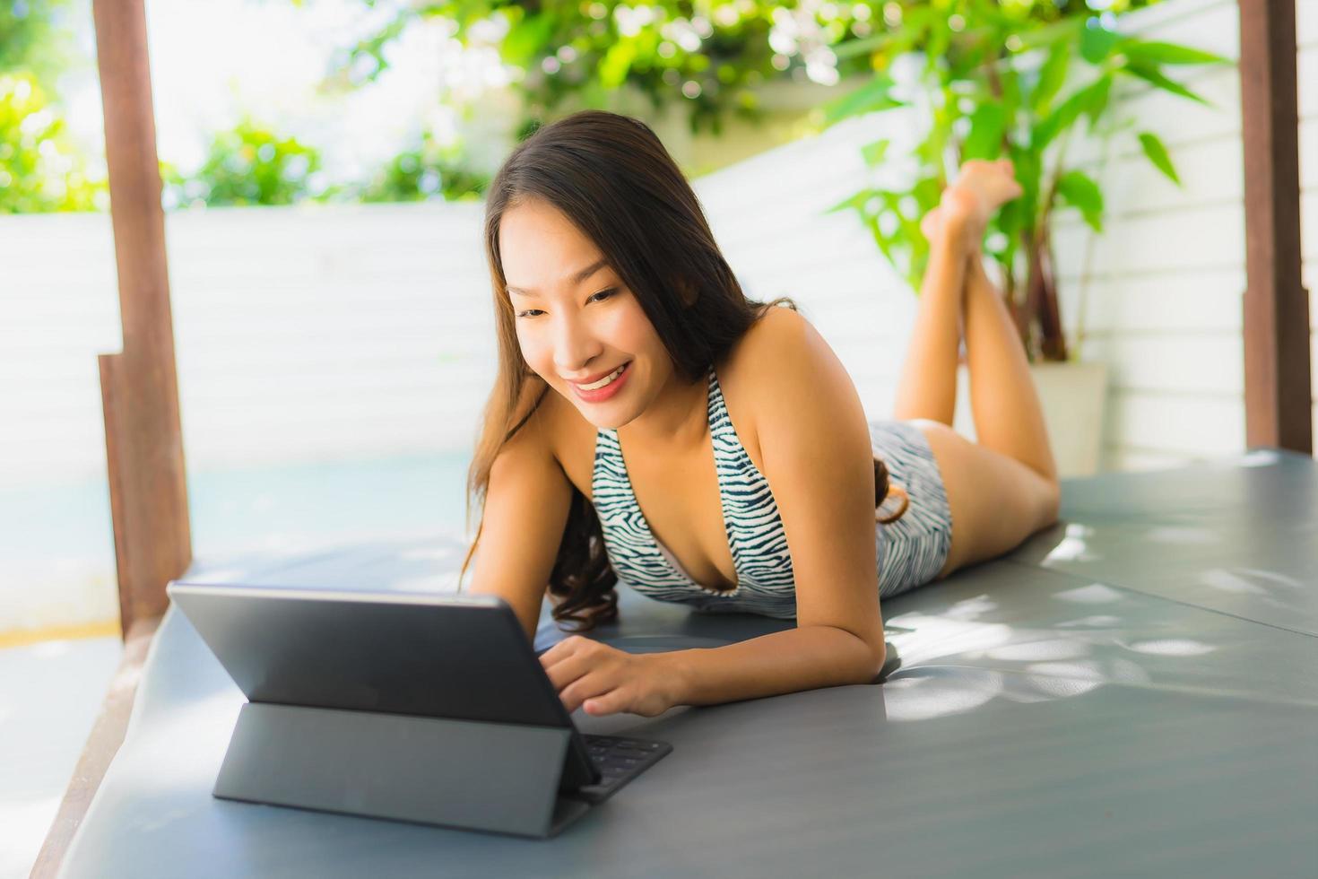 Portrait beautiful young asian woman happy smile using tablet or smart device around swimming pool photo