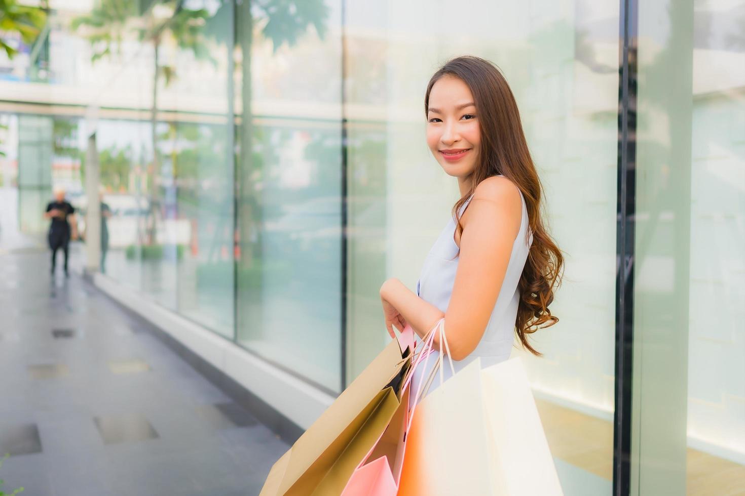 Retrato hermosa joven asiática feliz y sonrisa con bolsa de compras de los grandes almacenes foto