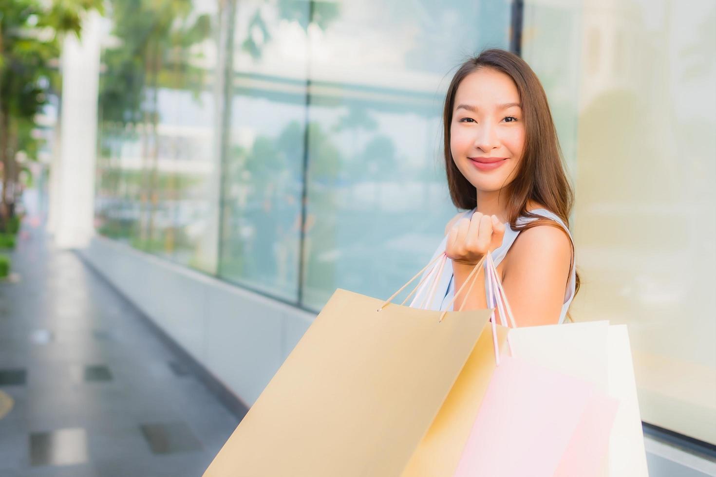 Retrato hermosa joven asiática feliz y sonrisa con bolsa de compras de los grandes almacenes foto