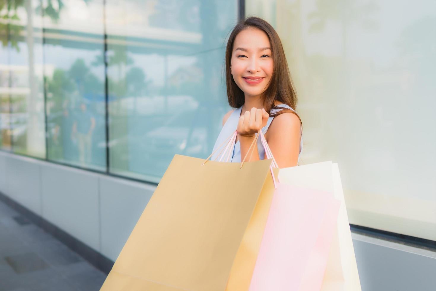 Retrato hermosa joven asiática feliz y sonrisa con bolsa de compras de los grandes almacenes foto