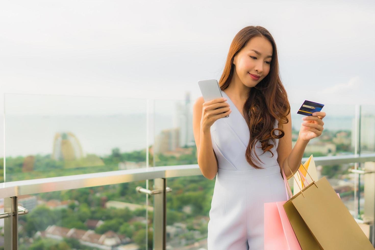 retrato, hermoso, joven, mujer asiática, feliz, y, sonrisa, con, tarjeta de crédito, y, móvil, o, teléfono inteligente, y, bolsa de compras foto