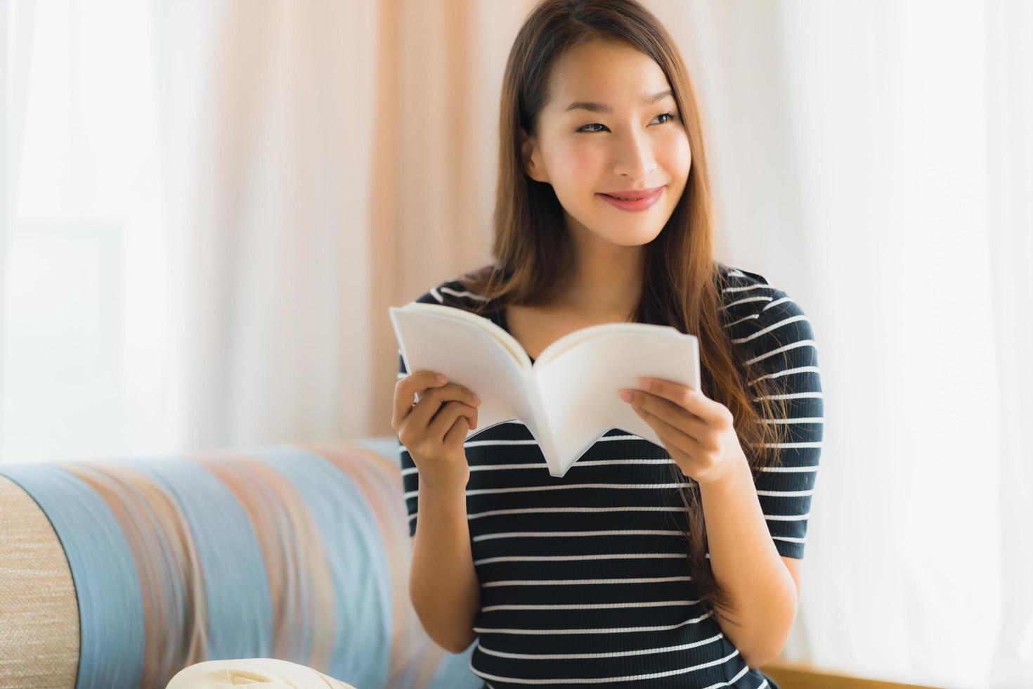 Portrait beautiful young asian woman reading book in on sofa in living room area photo