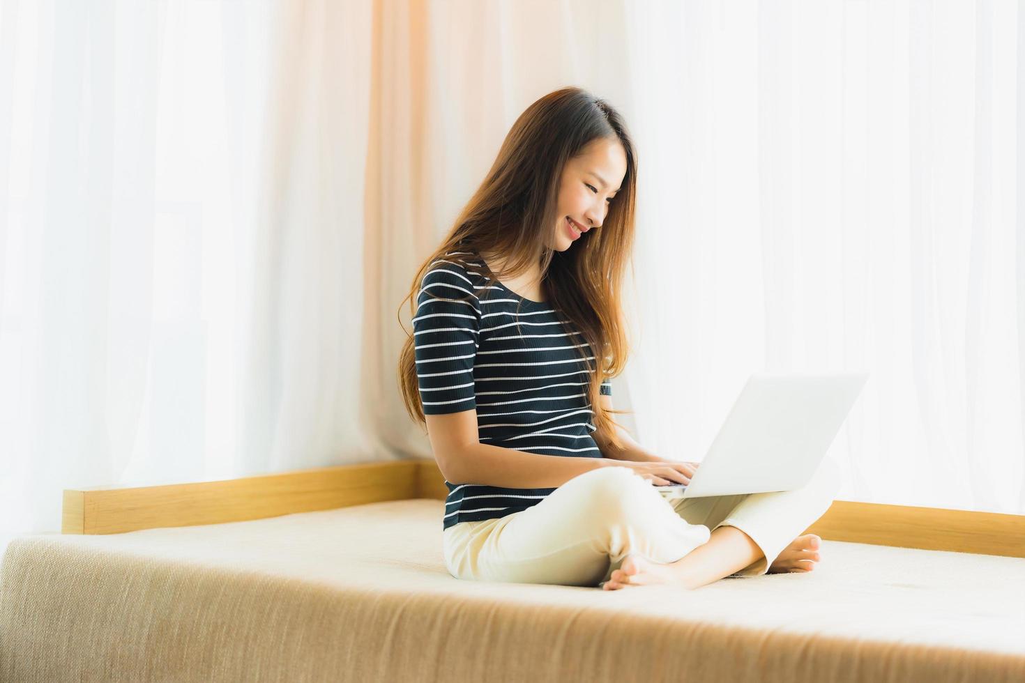 Portrait beautiful young asian woman using computer notebook or laptop on sofa in living room photo